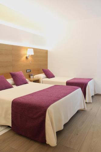 two beds in a hotel room with purple sheets at Hotel La Noyesa *** Superior in O Grove