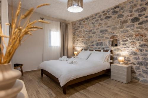a bedroom with a large bed and a stone wall at Anemolithos Mani's House in Areopoli