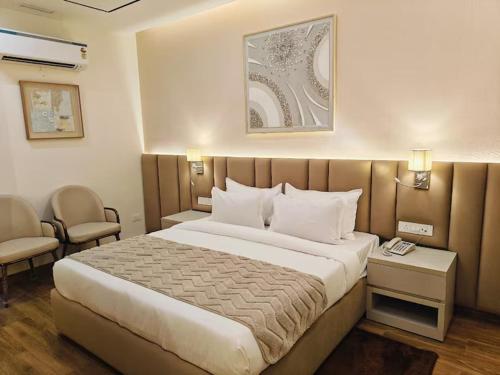 a hotel room with a large bed and two chairs at Hotel Pallavi Grand in Panchkula