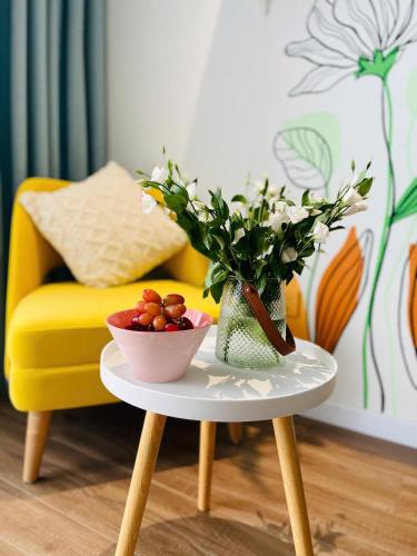 a table with a bowl of fruit and a vase of flowers at Sweet Home in Gò Ba Quần