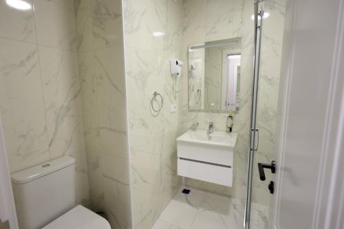 a white bathroom with a toilet and a sink at Mira Seaview Studio Apartment in Batumi in Batumi
