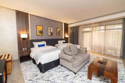 a hotel room with a bed and a couch and a chair at Virunga Inn Resort & Spa in Kinigi