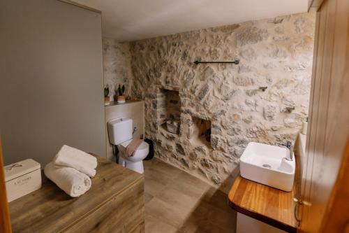 a bathroom with a sink and a stone wall at Anemolithos Mani's House in Areopoli