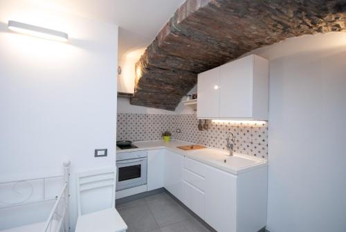 a kitchen with white cabinets and a brick ceiling at Casa Di Mezzo by Arbaspàa in Manarola