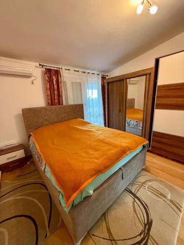 a bedroom with a bed with an orange blanket on it at King Apartment in Sutomore
