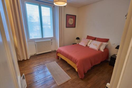 a bedroom with a red bed and a large window at Ma maison du port in Guipry-Messac