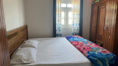 a small bedroom with a bed with a blanket on it at Madu Guest in Nuwara Eliya