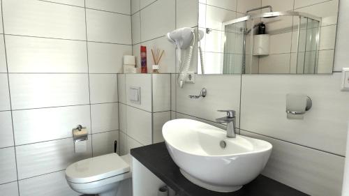 a white bathroom with a sink and a toilet at Bele Lofts in Karmėlava