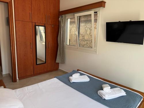 a bedroom with a bed and a tv and towels at Leka Village Our Hidden Gem in Léka