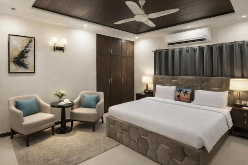 a bedroom with a large bed and two chairs at Hotel White Castle Islamabad in Islamabad
