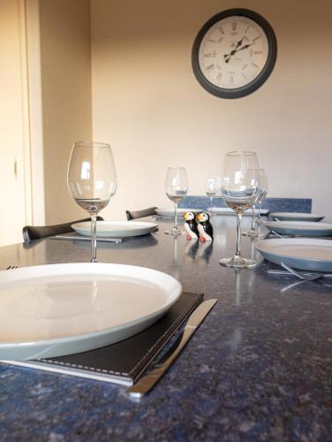 a table with wine glasses and a clock on the wall at Havrock in Orkney