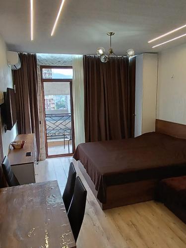 a bedroom with a bed and a table and a window at ევრო პალას გონიო in Kvariati
