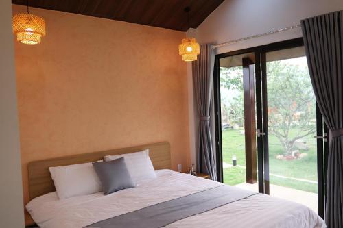 a bedroom with a bed and a large window at The C'mon Mộc Châu in Làng Môn