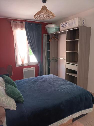 a bedroom with a blue bed and a window at Le Petit Marais in Échiré