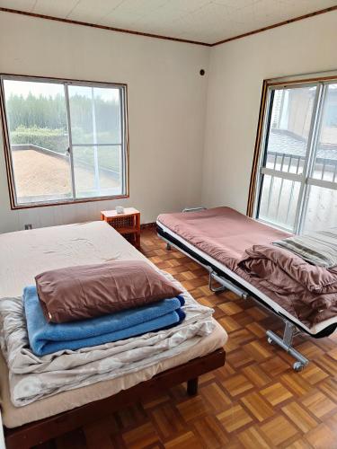 two beds in a room with two windows at 海っぺり宮崎 in Miyazaki