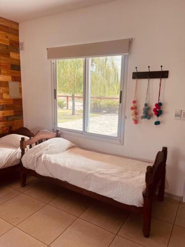 two beds in a room with a window at Cina Cina, casita in Zonda
