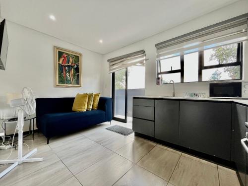 a living room with a blue couch and a kitchen at No 6 On Cladon # Jadde Apartments in Chartwell
