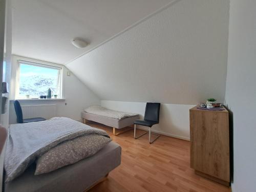 a bedroom with a bed and a desk and a window at Michelle's Yellow house in Ilulissat