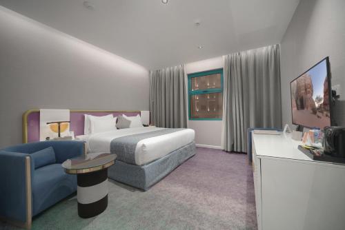 a hotel room with a bed and a blue couch at Marvelous Hotel in Tabuk