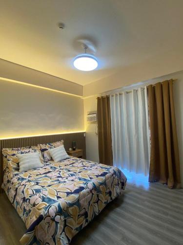a bedroom with a bed and a large window at Iam Cozy Condo Mactan Airport in Lapu Lapu City