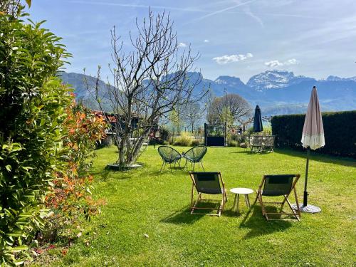 a lawn with chairs and an umbrella and a table at Le Chalet de la Plage in Sévrier