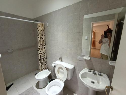 a person taking a picture of a bathroom with a toilet and sink at La Morenita dos dormitorios in Chilecito