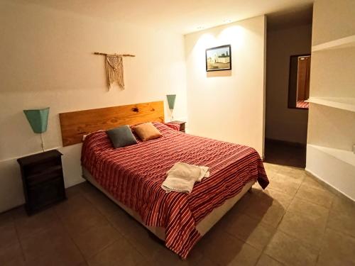 a bedroom with a large bed with a red blanket at La Morenita dos dormitorios in Chilecito