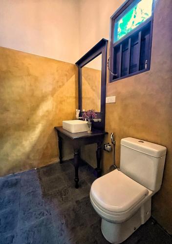 a bathroom with a toilet and a sink and a window at Ceylon Little Paradise in Hikkaduwa
