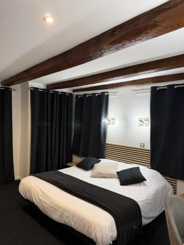 a bedroom with a large bed with black curtains at Hotel La Basilique in Épinal