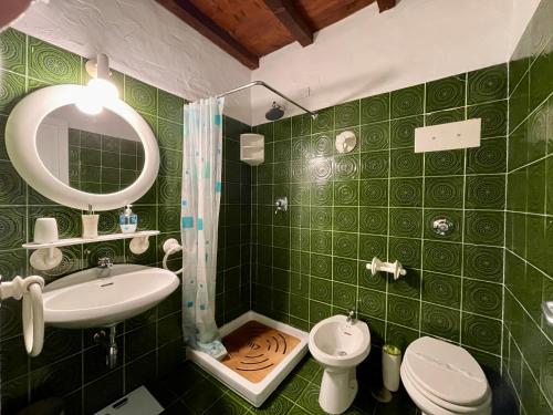 a green tiled bathroom with a sink and a toilet at Punta Est - Trilo LAVANDA Terrazza & Piscina in Capo Coda Cavallo