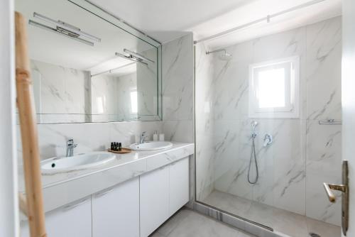a white bathroom with two sinks and a shower at White Pearl Mykonos in Mikonos