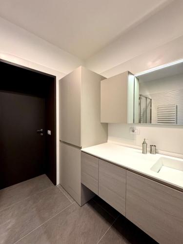 a white kitchen with a sink and a mirror at Casa Mirit - Nesso in Nesso