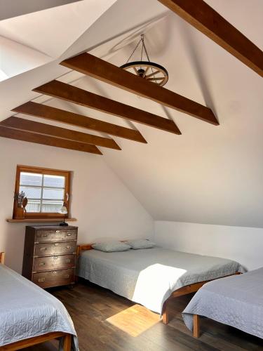 a attic bedroom with two beds and a chandelier at Sodyba Viltis in Bikavėnai