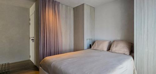 a small bedroom with a bed with white sheets at Groenendijk 8 in Oostduinkerke