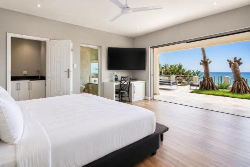 a bedroom with a white bed and a view of the ocean at Vetho House Villa Ballito in Ballito