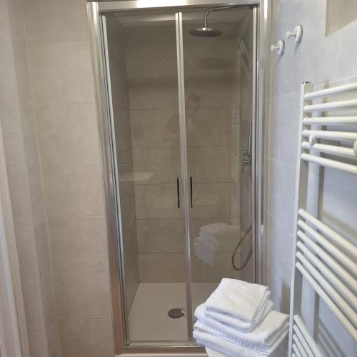 a shower with a glass door and some towels at Hotel Due Gemelli in Riomaggiore