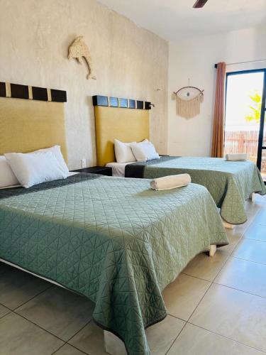 two beds in a hotel room with green blankets at CASA DELFINES RIO LAGARTOS in Río Lagartos