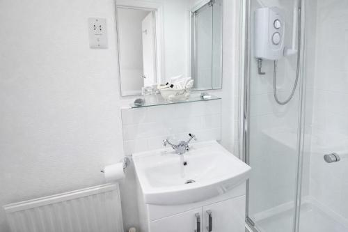 a white bathroom with a sink and a shower at Ferndale Lodge in Torquay