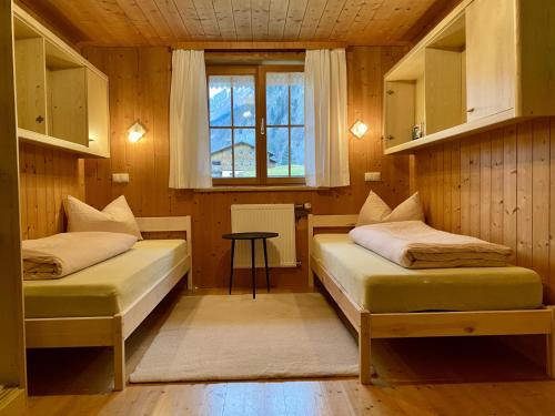 two beds in a room with a window and a table at Rüf Stefanie in Au im Bregenzerwald
