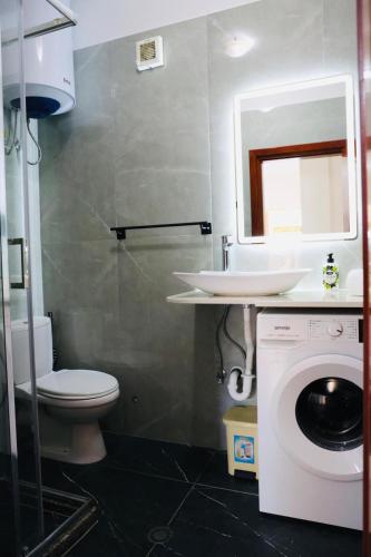 a bathroom with a toilet and a sink and a washing machine at Gees House in Golem