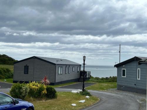 two houses and a car parked in front of the ocean at 820 Ocean View, Lydstep Haven Beach in Tenby