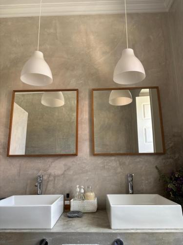 two sinks in a bathroom with two mirrors and two lights at Casa da Mata in Torres Novas