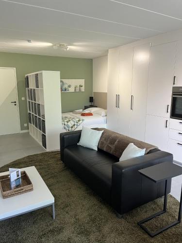 a living room with a black couch and a bed at Business Accommodation 'Comfort Living' in Geel