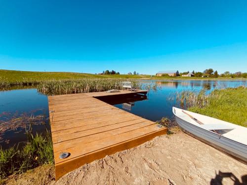 a wooden dock with a boat on a lake at Dom BAnia Mazury SPA in Kukowo