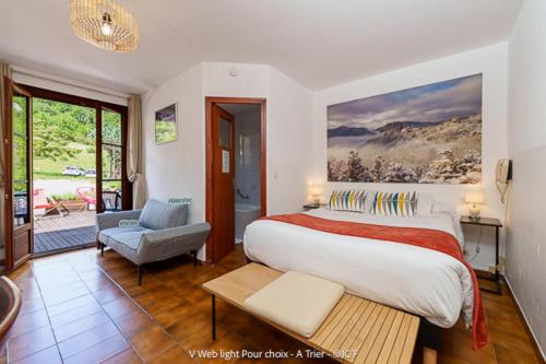 a bedroom with a large bed and a chair at Auberge du Point Sublime in Rougon