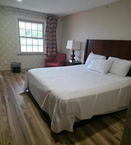 a bedroom with a bed and a chair and a window at Dover Inn in Dover