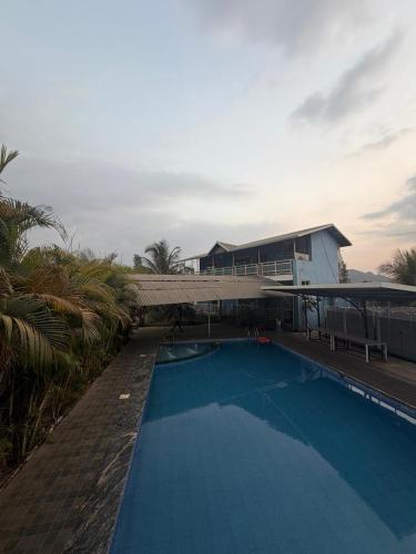 a large blue swimming pool with a house in the background at Bhogwal farm house in Karjat