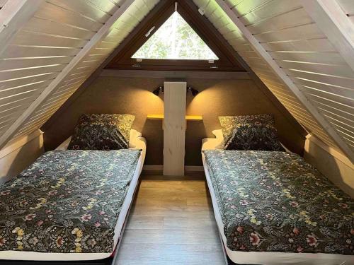 two beds in a attic room with a window at Chalet Z en Alsace in Barr