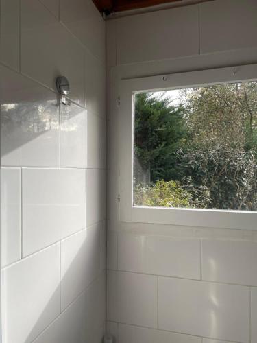 a bathroom with a window and white tiled walls at Maison Maubuisson proche du lac de Carcans in Carcans