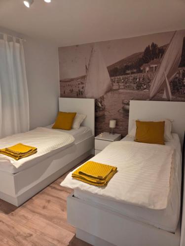 two white beds in a room with a painting on the wall at Holiday house Villa Marea with jacuzzi in Crikvenica